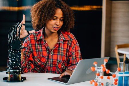 Portrait of a Black teenage student in a classroom learning about a robotic arm for her engineering project. She skillfully controls the arm showcasing intelligence and innovation in technology.の写真素材