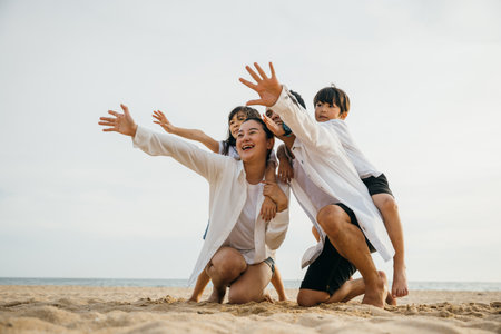 Happy family at the beach enjoying summer holidays. Parents with children laughing playing and looking at the sea. Travel and relaxation concept captured in this joyful momentの写真素材