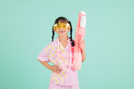 Songkran holiday happiness with cheerful child in glasses and floral shirt holding water gun,...