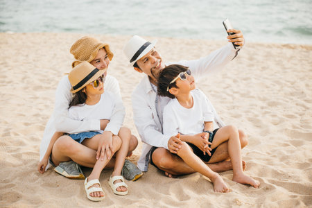 Summer smiles and family fun on the beach as they capture a delightful selfie near the sea. Laughter joy and togetherness define this perfect moment during their travel adventure.の写真素材