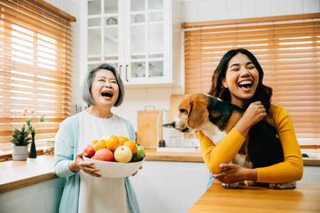 A happy Asian grandmother, her daughter, and young woman share a playful kitchen scene with their Beagle dog, highlighting the fun, happiness, and family bonding over pet care.の写真素材