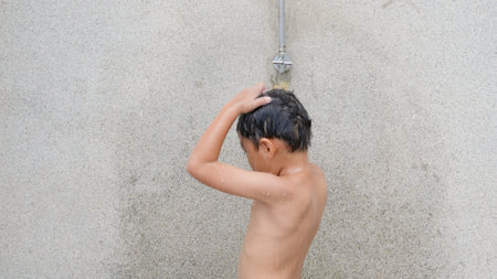 Asian child little boy taking shower at the swimming pool resort, Happy kid after swim he cleaning body refreshing and hyginic in tropical resort during family summer vacationの写真素材