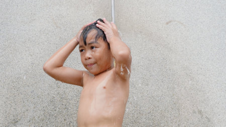 Asian child little boy taking shower at the swimming pool resort, Happy kid after swim he cleaning body refreshing and hyginic in tropical resort during family summer vacationの写真素材