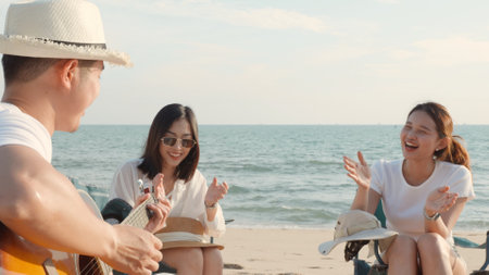 Happy friend have fun playing guitar and clap in camp they smiling together in holiday on sand beach...