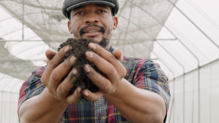 Farmer holding pile of arable black soil. Close up of expert hand of farmer checking soil health before growth a seed of vegetable, Business or ecology conceptの写真素材