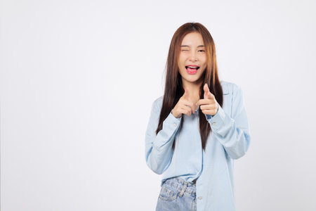 Cheeky woman makes a finger gesture as friendly woman winks and smiles, playfully pointing like she saying what up or you are the one, isolated on white background.の写真素材