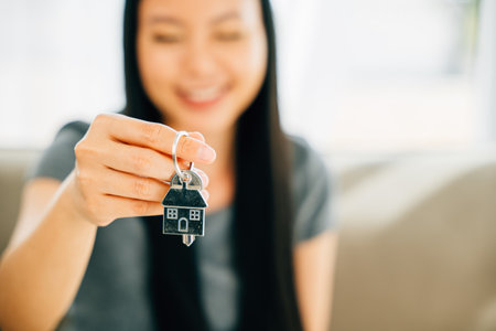 A female hand displays a house key exuding success and security in real estate. Symbolizing achievement confidence and the joy of homeownership.の写真素材