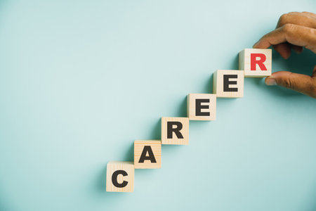 Career planning and growth. A hand places a wooden cube block labeled CAREER on a vibrant blue background, offering copy space for text and emphasizing the significance of business success.の写真素材