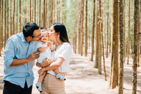 A man and woman holding a baby in a forestの写真素材