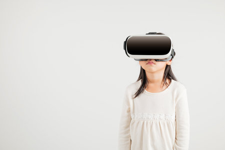 Smiling young kid girl confidence excited wear VR headset device during virtual reality experience isolated white background, Asian happy portrait kindergarten child playing video game studio shotの写真素材