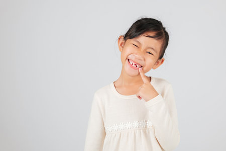 A happy child showcases a tooth gap by pointing at it. The dentist helps kids understand the stages of tooth loss and how to care for their growing tooth gap.の写真素材