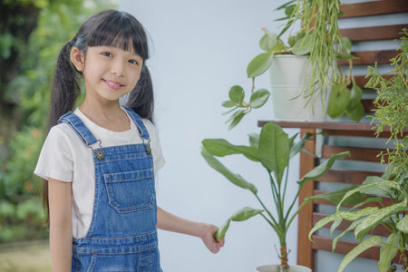 Asian young attractive girl standing beside a green potted plant at home held, World Environment Day conceptの写真素材