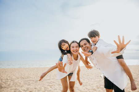 Beach fun with a happy family. Parents and children laughing playing and enjoying the sea. Summer holidays represent joy freedom and travel. A moment of relaxation and happinessの写真素材