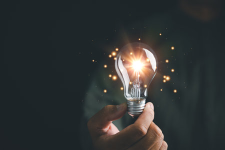 A man holding a glowing light bulb, symbolizing the idea of innovation and creativity. connection between bright concepts and successful solutions. imaginative thinking in business and technology.の写真素材