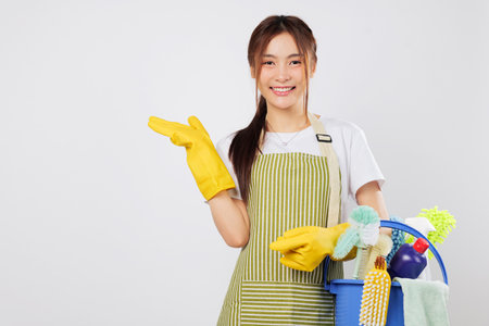 Cleaning supplies gear ready as she holds a bucket and gestures with her palm. Her cleaning skills bring sparkle and shine to every home. isolated studio white background empty space for your textの写真素材
