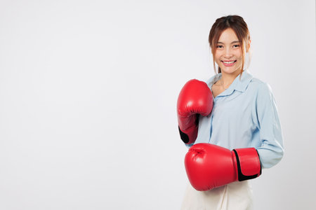 Boxing stance of a smiling Asian young woman Happy with red boxing glove. Fit and confident business boxer shows powerful fighting energy. isolated studio white backgroundの写真素材