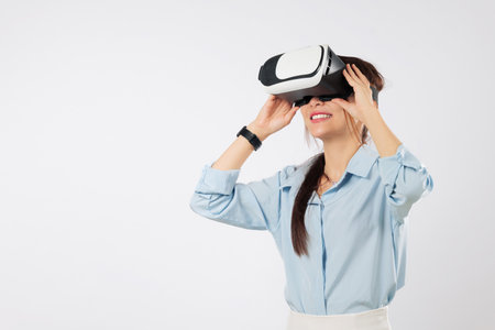 Young asian woman using vr headset for future game tech, teenage experience with virtual reality, much gesticulating hands and exploring cyberspace in vr, isolated studio white backgroundの写真素材