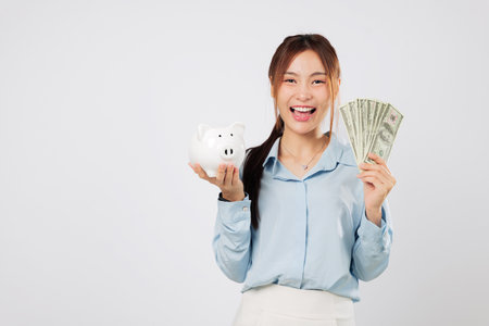 Portrait Happy young woman hold piggy bank and money bills, excited by money save goals and finance planning, celebrating smart budget control and investment success savings. isolated white backgroundの写真素材