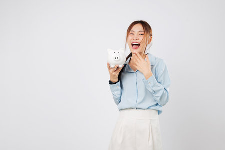 Happy woman holding piggy bank smiling excited with piggy save money win and showing success in finance, bank planning, and smart investment. isolated studio white backgroundの写真素材