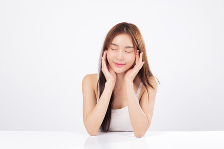 Skin hydration and clean skin are highlighted by a woman with a serene smile gently touching her face, portraying a skincare concept isolated studio white backgroundの写真素材