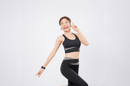 Dance takes over as this energetic woman listens to her favorite tune. Her smile widens as she begins to dance again, enjoying the healthy lifestyle she loves. isolated studio white backgroundの写真素材