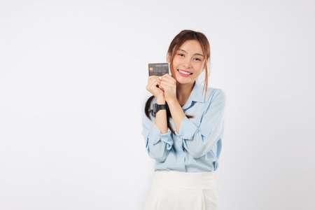 Happy Asian woman with credit card, money payment and bank card, presenting her hold card, smiling for online business payment, and showing card to pay a merchant, isolated studio white backgroundの写真素材
