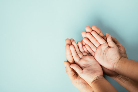 Family hands stack in close-up top view isolated background. Parents and child hold empty space together expressing support on Family and Parents Day.の写真素材