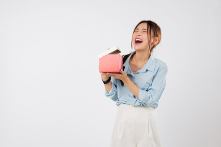 Gift moment captured as woman opens surprise present with excitement and later discovers a second gift tucked under the wrapping. isolated studio white backgroundの写真素材