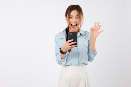 Happy asian woman shopping with credit card, mobile phone shows emotions of surprise winning. Young lady looks excited, sharing a special card online on social media, isolated studio white backgroundの写真素材