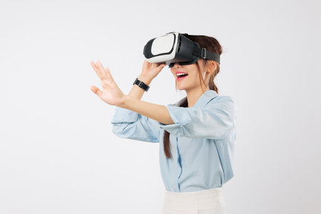 VR headset virtual reality for Asian woman in glasses game future; happy girl touches screen, interacts in virtual world, enjoying vr experience, and online app, isolated studio white backgroundの写真素材