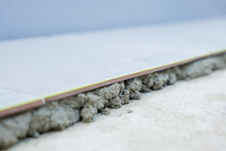 A detailed view of a gray tile securely laid on gray mortar, showcasing the evenness and professional finish of the flooring process.の写真素材