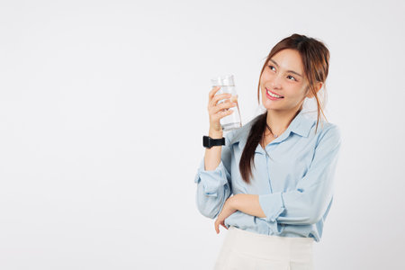 Woman glass hold happy asian smile young lifestyle care with water, a model shows hydration benefits with crystal clear water in hand with care, isolated studio white backgroundの写真素材