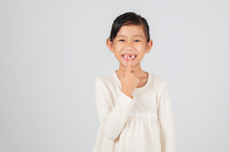Happy child pointing to a tooth gap with joy. The dentist discusses tooth loss and the importance of monitoring the growing tooth gap for healthy teeth. isolated white backgroundの写真素材