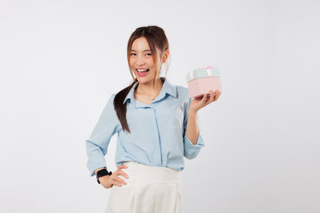 Gift brings happiness to excited woman as she holds pink ribbon box on side palm with smile, posing for a portrait with her special gift box on a joyful day. isolated studio white backgroundの写真素材