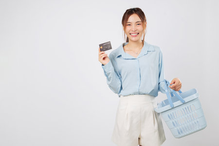 Shopping smile woman Excited holding basket and credit card, excited for more shopping at supermarket with finance goals and secure money spending plan. isolated studio white backgroundの写真素材