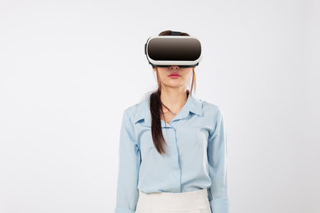 Young woman wearing virtual reality glasses explores future tech, excited asian girl using vr device and smiling, experiencing vr through innovative technology, isolated studio white backgroundの写真素材
