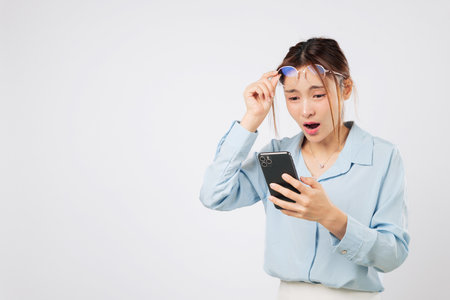 Vision problem woman holding glasses and looking at phone screen, blurred vision loss causes blurry sight and bad eyesight while reading text messages. isolated studio white backgroundの写真素材