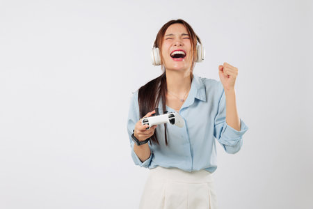 Game play moment of a teen young woman with headphones, cheering in joy after tough game level completed with success and full emotion. isolated studio white backgroundの写真素材