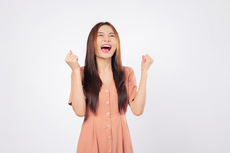 Success empowered by success she celebrates her moment with a raised fist and a bright excited smile showing confidence and professional victory isolated studio white backgroundの写真素材