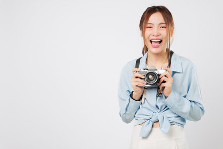 Tourist girl laughing, excited tourist holding camera on summer vacation. Happy Young woman enjoys holiday journey capturing every photo with passion. isolated studio white backgroundの写真素材