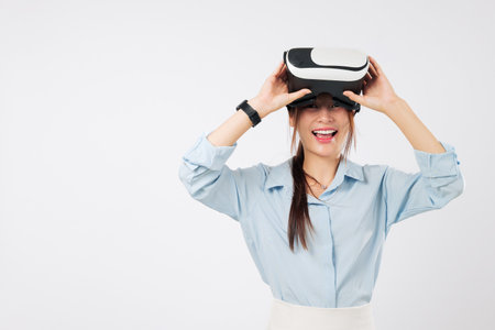 Asian woman taking vr glasses, removing headset with astonishment, after experiencing virtual reality, on clean white backdrop, enjoying vr game play session, isolated studio white backgroundの写真素材