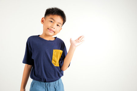 Asian happy portrait cute young boy smile presenting product holding something on palm away side, studio shot isolated on white background with copy space, primary child show hand gestureの写真素材