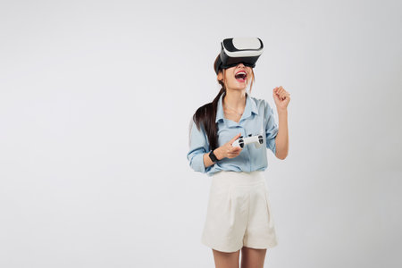 Game becomes real as Excited young Asian woman in VR headset plays console game, fully immersed in futuristic virtual dimension. isolated studio white backgroundの写真素材