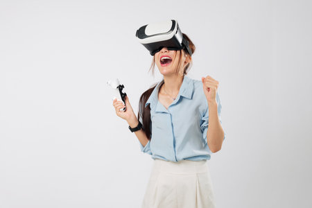 Game success for Excited young Asian woman using joystick controller in VR headset game, thrilled by...