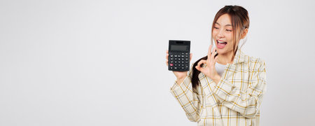 Holding one calculator and showing another, Asian woman gives OK gesture symbolizing business...