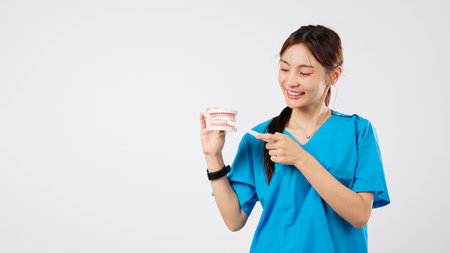 Smiling asian dentist woman, doctor, model, holding toothbrush, demonstrating proper teeth brushing...