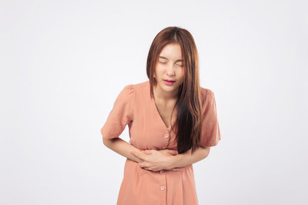 Stomach symptoms and stomach ache expressed in the portrait of an Asian woman showing abdominal pain...