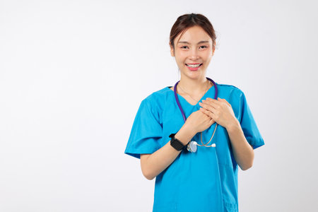 Doctor healthcare asian woman with a stethoscope chest and hands, smiling nurse with a grateful gesture, shows sympathy as a friendly nurse in uniform, headshot isolated studio white backgroundの写真素材