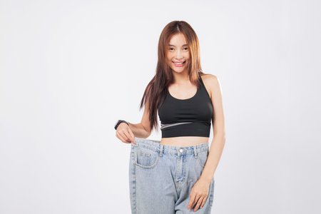 Thin waist revealed as young woman shows off oversized pants with pride. Her thin frame reflects...