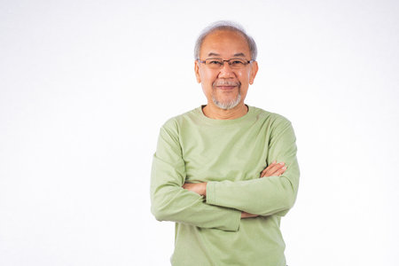 Portrait grey haired smiling senior man with arms crossed studio shot isolated on white background, elderly arms folded lifestyle freedom relax retirement conceptの写真素材